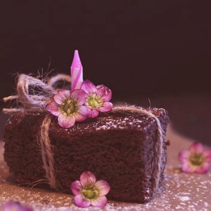 Fatia de nega maluca de liquidificador enfeitada com flores e laços de barbante.