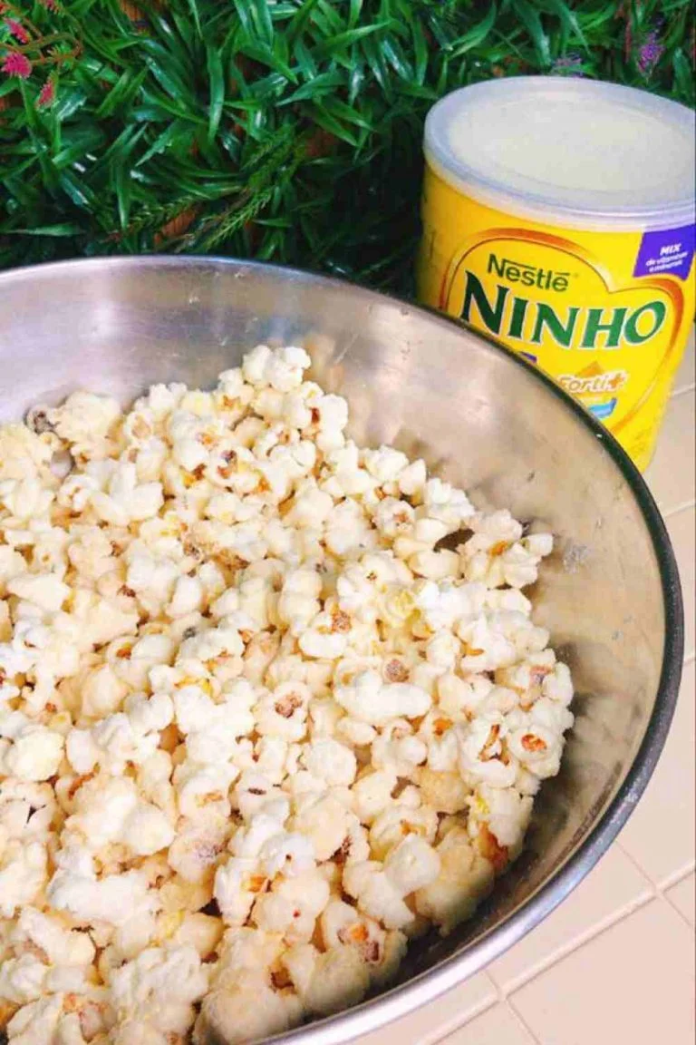 Pipoca Gourmet de Leite Ninho já pronta, em uma bacia de metal com uma lata de leite em pó ao lado